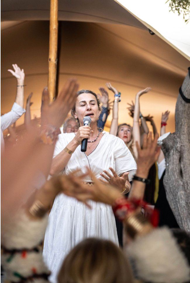 Lara and the circle — hands raised in song