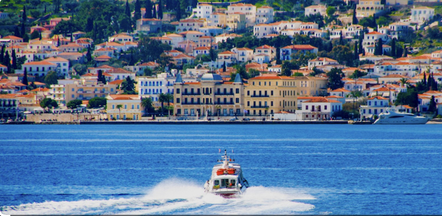 Spetses waterfront at the Poseidonion, with a boat on blue water
